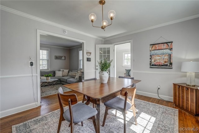 dining space with a notable chandelier, crown molding, baseboards, and wood finished floors