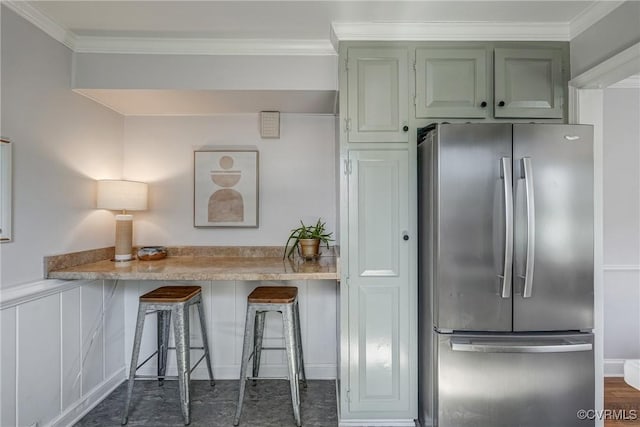 kitchen featuring a kitchen bar, light countertops, freestanding refrigerator, and ornamental molding