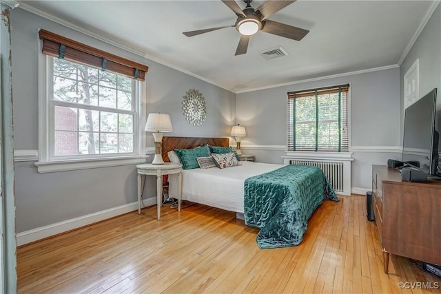 bedroom featuring visible vents, radiator, baseboards, ornamental molding, and hardwood / wood-style flooring