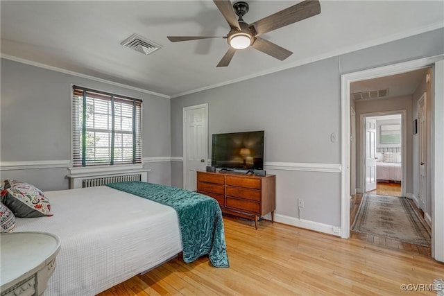 bedroom featuring light wood-type flooring, visible vents, ornamental molding, and radiator heating unit