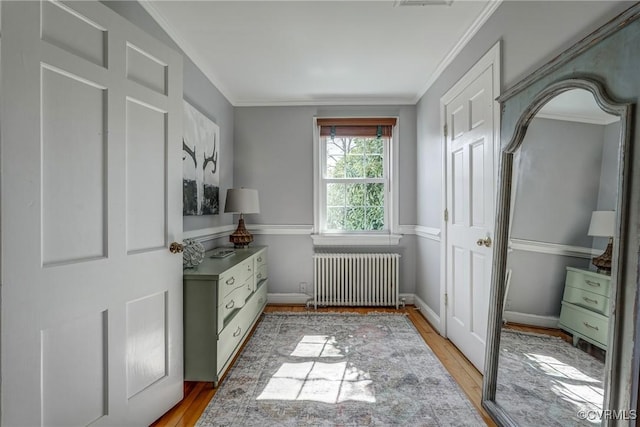 interior space featuring crown molding, radiator heating unit, and light wood-style floors