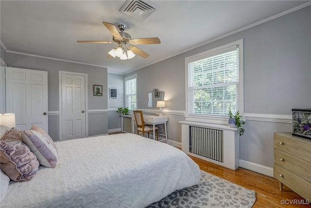 bedroom with visible vents, ornamental molding, wood finished floors, radiator heating unit, and baseboards