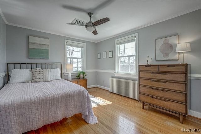 bedroom featuring radiator, light wood-style flooring, and ornamental molding