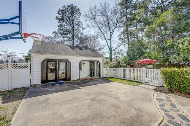 exterior space featuring a gate, a shingled roof, and fence