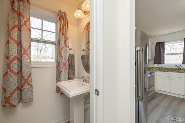 bathroom with wood finished floors and a healthy amount of sunlight