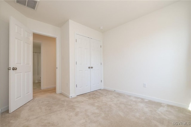 unfurnished bedroom with light colored carpet, visible vents, a closet, and baseboards