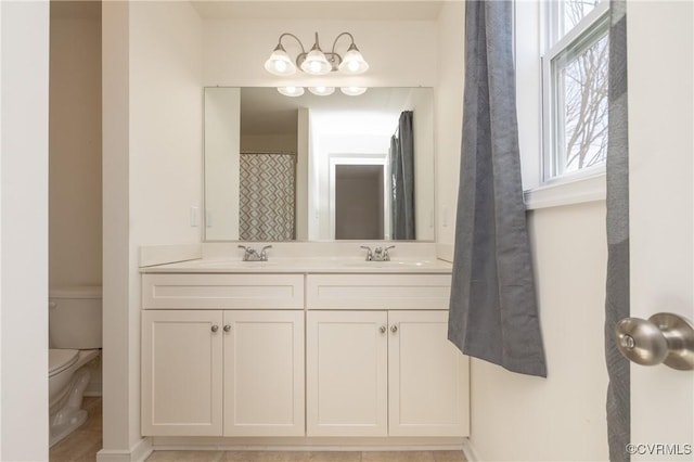 full bathroom with double vanity, toilet, and a sink