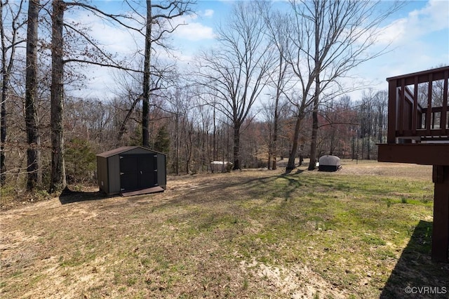 view of yard featuring a storage shed, an outbuilding, and a view of trees