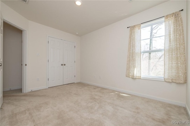 unfurnished bedroom with light colored carpet, baseboards, and a closet