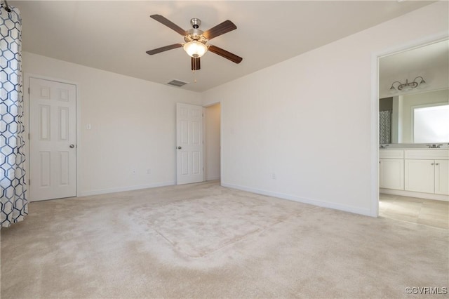 unfurnished bedroom with visible vents, baseboards, ensuite bath, a sink, and light carpet