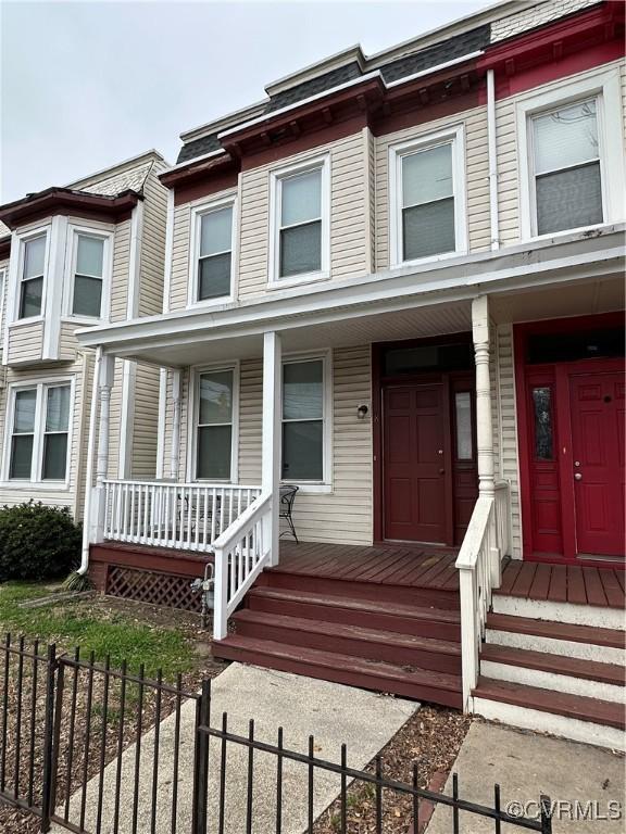 multi unit property with covered porch and a fenced front yard