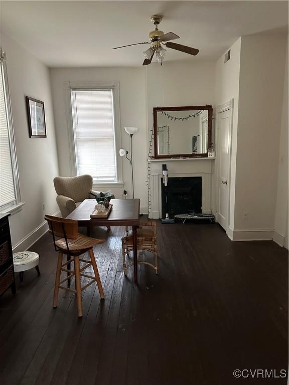 dining room with visible vents, a fireplace, baseboards, and hardwood / wood-style flooring