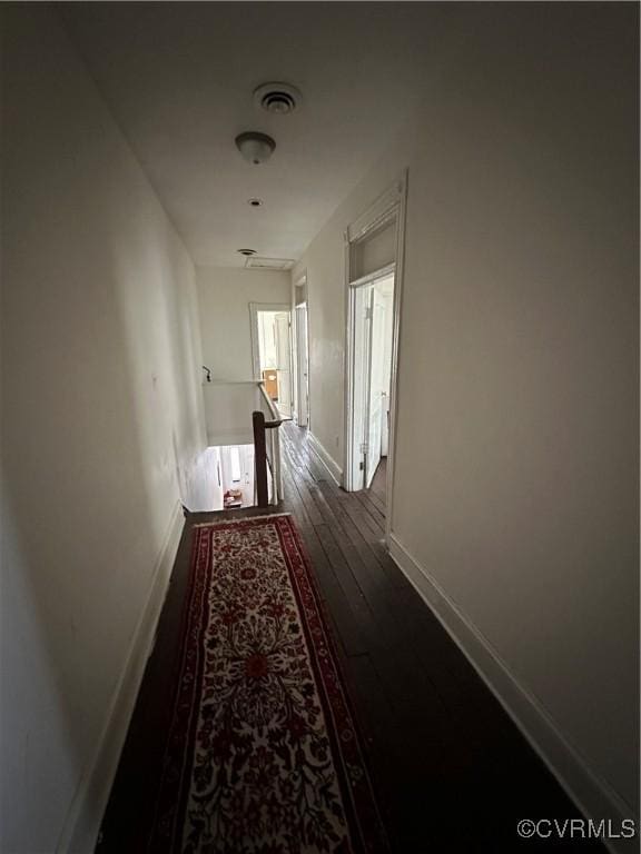 hall featuring visible vents, an upstairs landing, baseboards, and dark wood finished floors