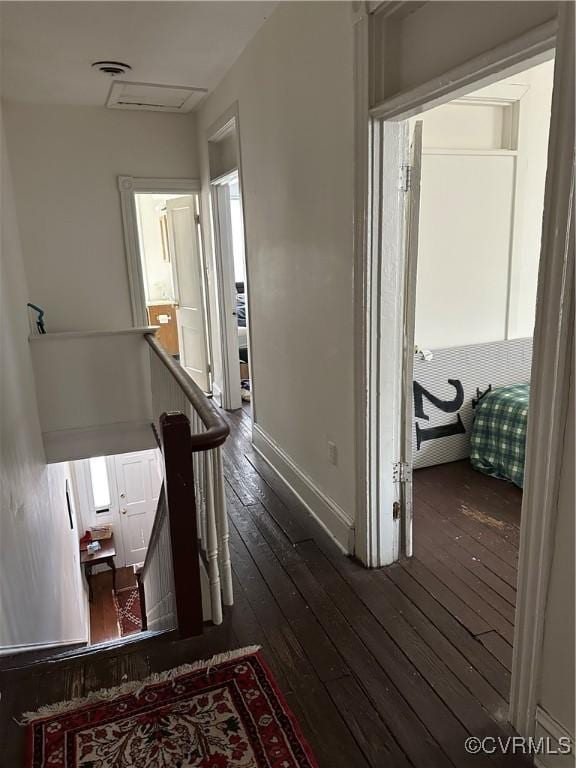 corridor featuring an upstairs landing, visible vents, dark wood finished floors, and baseboards