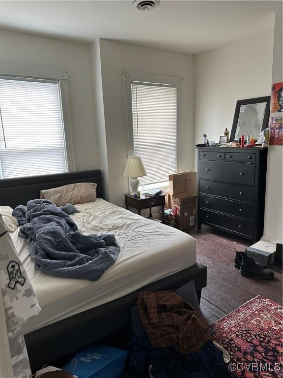 bedroom featuring dark wood-type flooring, multiple windows, and visible vents