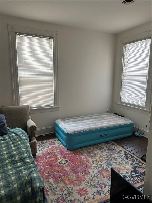 bedroom featuring multiple windows, baseboards, and wood finished floors