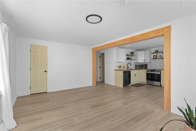 unfurnished living room with light wood-style flooring, baseboards, and a sink