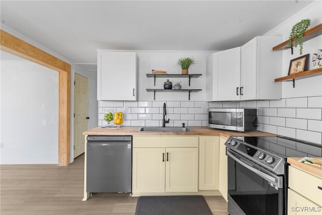 kitchen featuring open shelves, stainless steel appliances, wood counters, and a sink