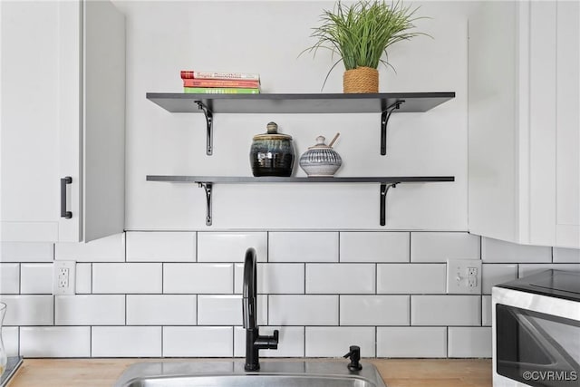 interior details with open shelves, white cabinetry, and a sink