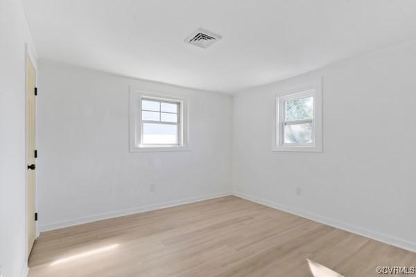 empty room featuring visible vents, baseboards, and light wood-style flooring