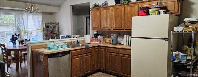 kitchen featuring brown cabinets, a sink, freestanding refrigerator, light countertops, and dishwasher