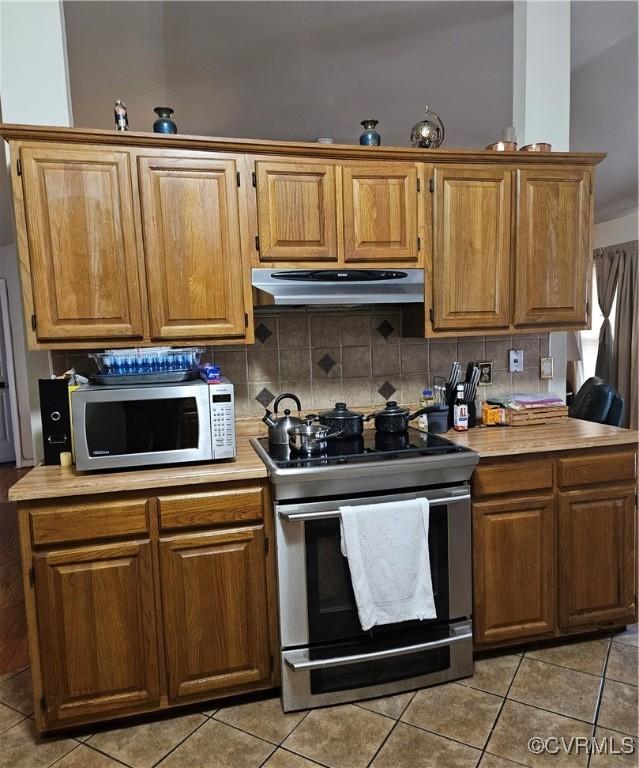 kitchen featuring under cabinet range hood, stainless steel appliances, light countertops, and tasteful backsplash