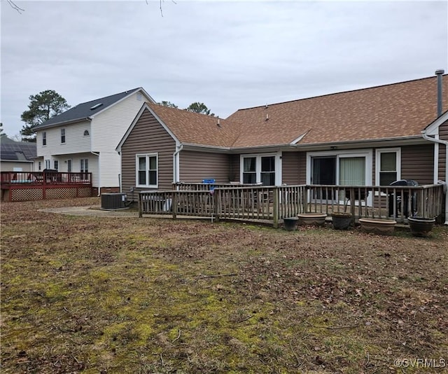 rear view of house with central AC, a wooden deck, and roof with shingles