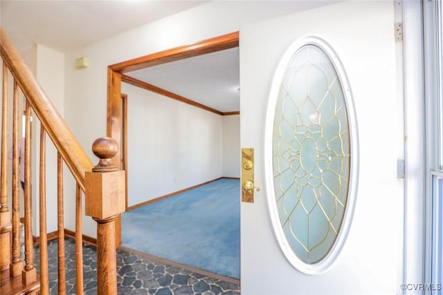 carpeted entrance foyer with crown molding, stairway, and baseboards