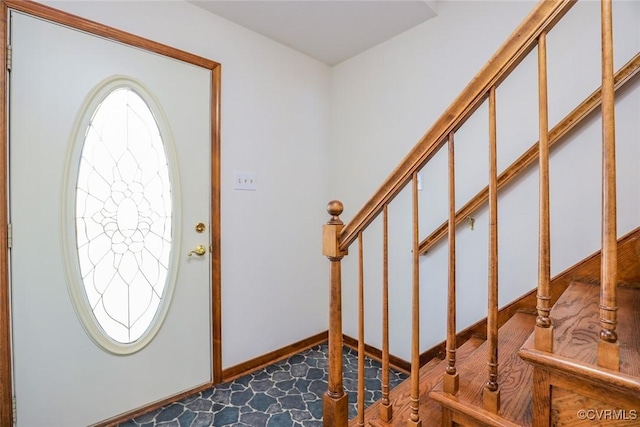 foyer entrance with stairs and baseboards