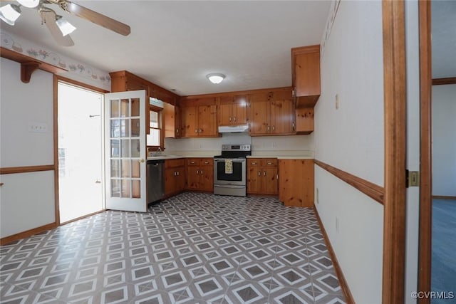 kitchen featuring baseboards, stainless steel appliances, light countertops, under cabinet range hood, and brown cabinets