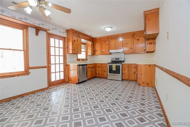 kitchen featuring under cabinet range hood, baseboards, appliances with stainless steel finishes, and light countertops