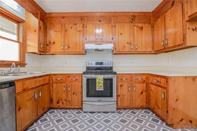 kitchen with under cabinet range hood, a sink, appliances with stainless steel finishes, light countertops, and light floors