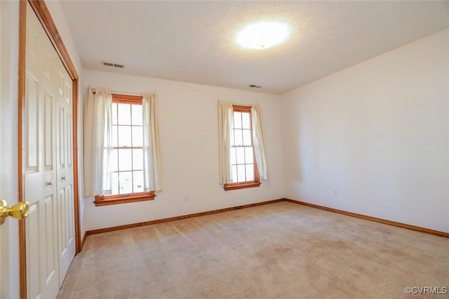 carpeted empty room featuring visible vents, plenty of natural light, and baseboards