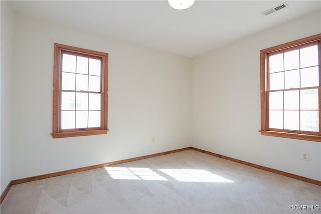 unfurnished room featuring baseboards, visible vents, and light carpet