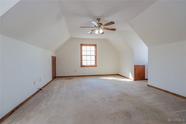 additional living space with vaulted ceiling, a ceiling fan, baseboards, and light carpet