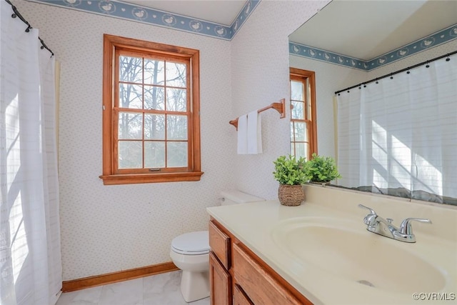 full bath with toilet, wallpapered walls, vanity, and baseboards