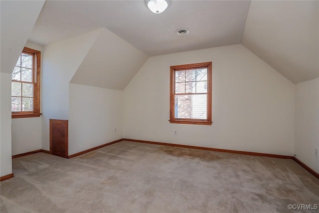 additional living space with light carpet, visible vents, baseboards, and lofted ceiling