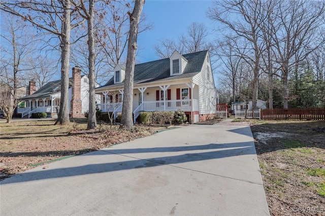 new england style home featuring a porch and fence