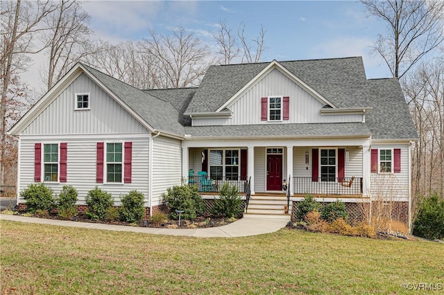 view of front of home with covered porch, board and batten siding, a front yard, and roof with shingles