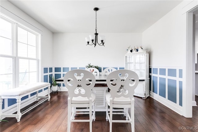 dining area featuring a notable chandelier, wood finished floors, and a decorative wall