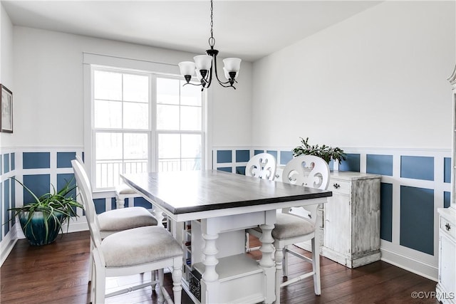 dining space featuring an inviting chandelier, dark wood finished floors, and a decorative wall