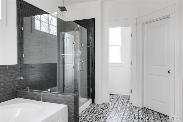 bathroom with a wealth of natural light, tile patterned flooring, a stall shower, and a garden tub