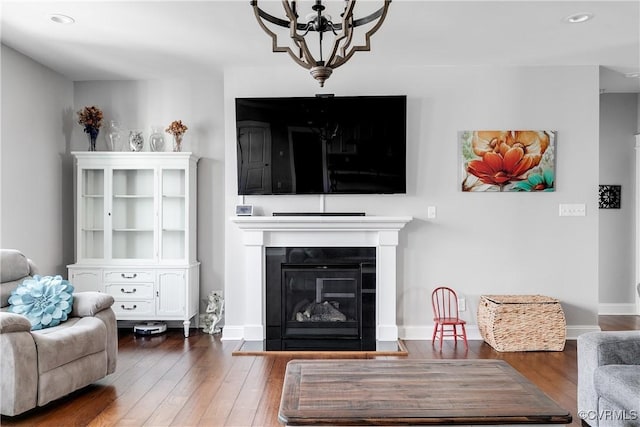 living room with baseboards, a glass covered fireplace, and hardwood / wood-style flooring