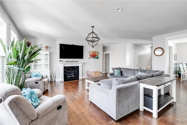 living room with a glass covered fireplace, hardwood / wood-style flooring, recessed lighting, and a chandelier