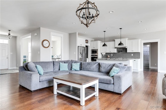 living area featuring recessed lighting, baseboards, dark wood-type flooring, and an inviting chandelier