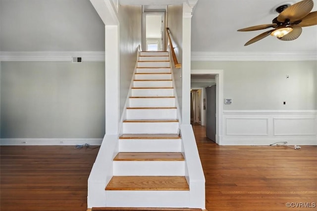 staircase featuring ceiling fan, wood finished floors, visible vents, and ornamental molding