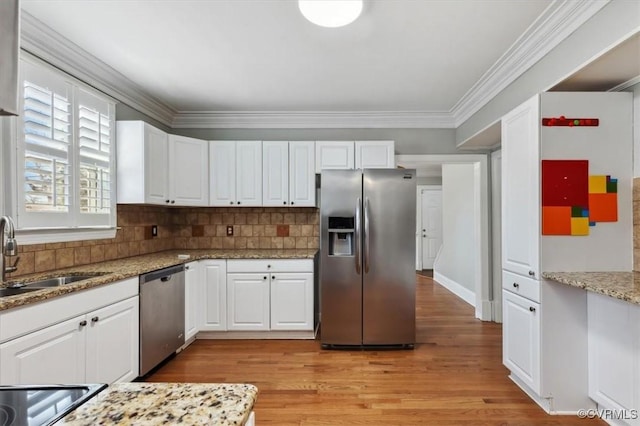 kitchen with crown molding, stainless steel appliances, light wood-style floors, white cabinetry, and a sink