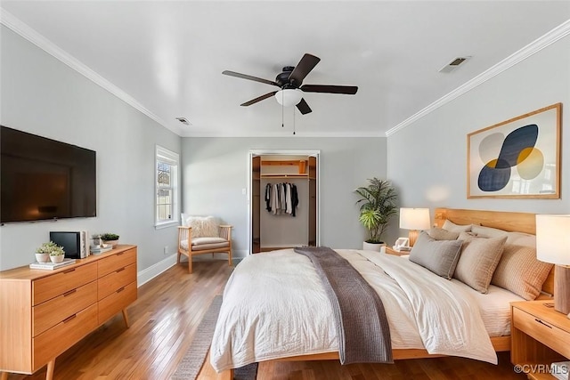 bedroom featuring baseboards, visible vents, light wood finished floors, and ornamental molding