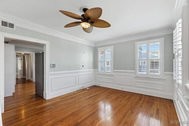 empty room featuring ceiling fan, visible vents, wood-type flooring, and ornamental molding