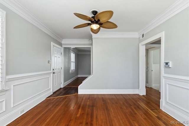 spare room with hardwood / wood-style flooring, a ceiling fan, visible vents, and ornamental molding